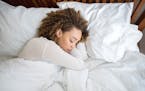 Tired African American woman sleeping in bed at home.