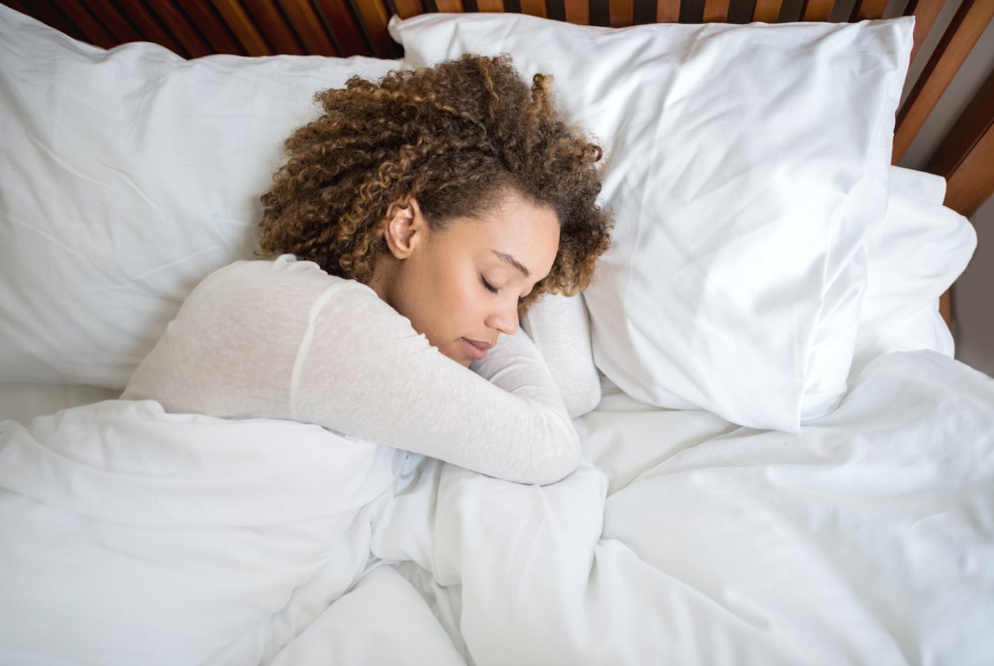 Tired African American woman sleeping in bed at home.