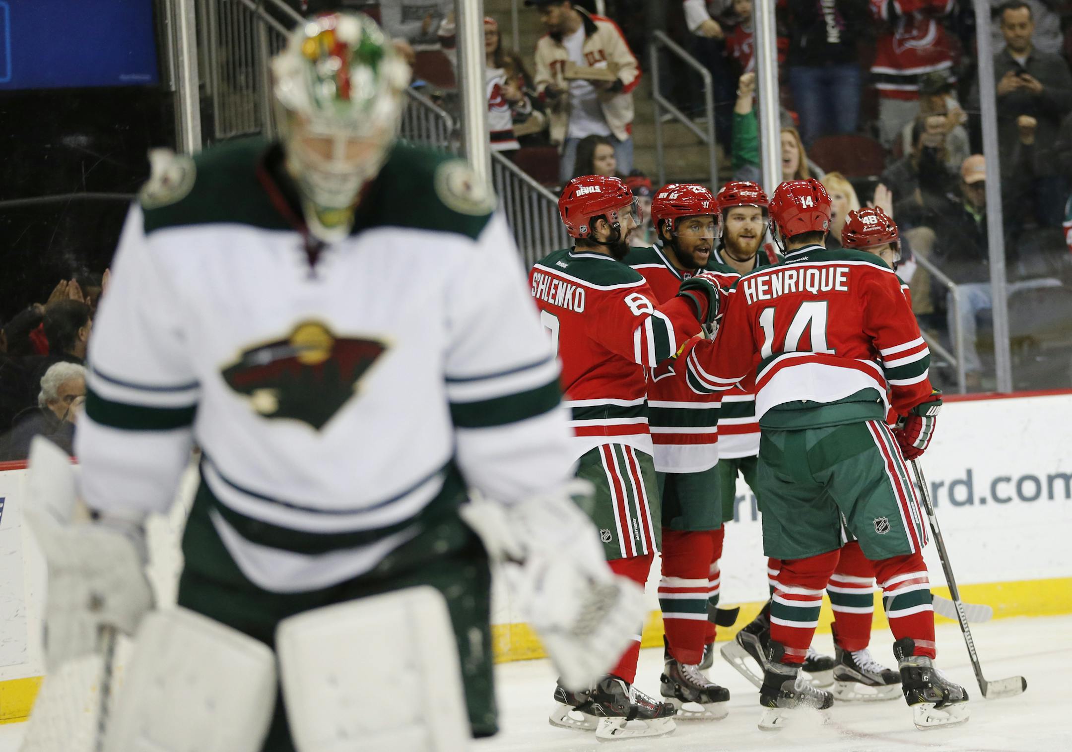 New Jersey Devils players celebrate a goal by Devante Smith-Pelly, center left, as Minnesota Wild goalie Darcy Kuemper skates away during the second period of an NHL hockey game, Thursday, March 17, 2016, in Newark, N.J. (AP Photo/Julio Cortez)