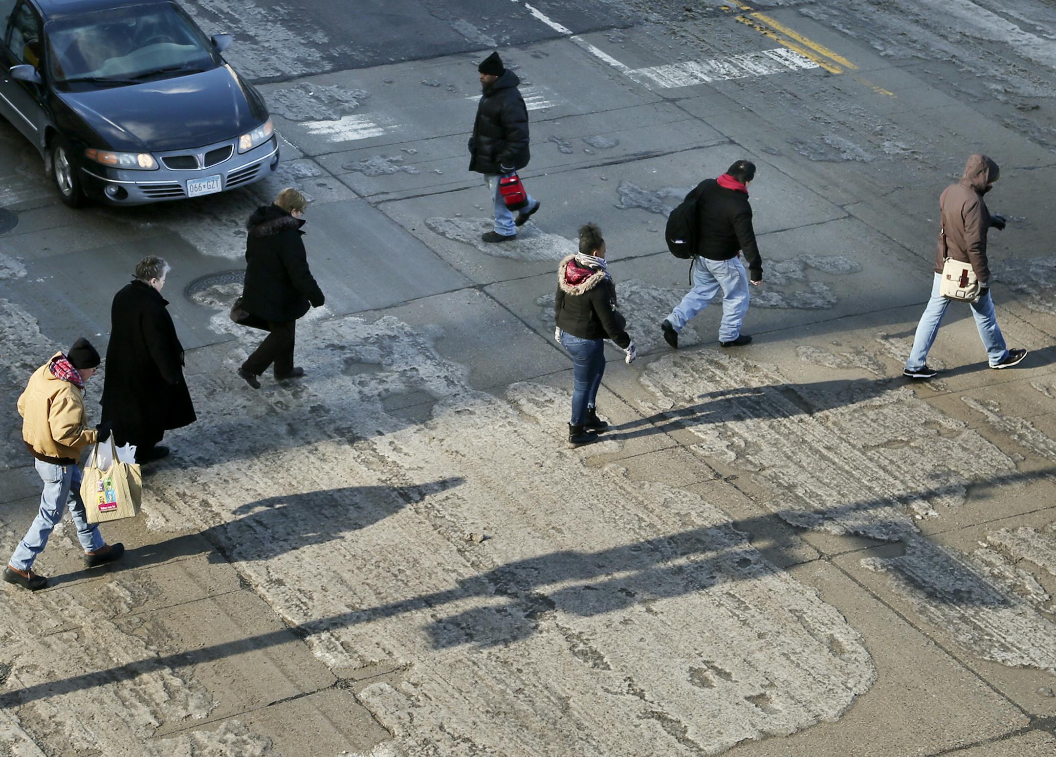 Winter has us in a rut: Pedestrians and cars have an uneven icy path to cross in downtown Minneapolis Tuesday.