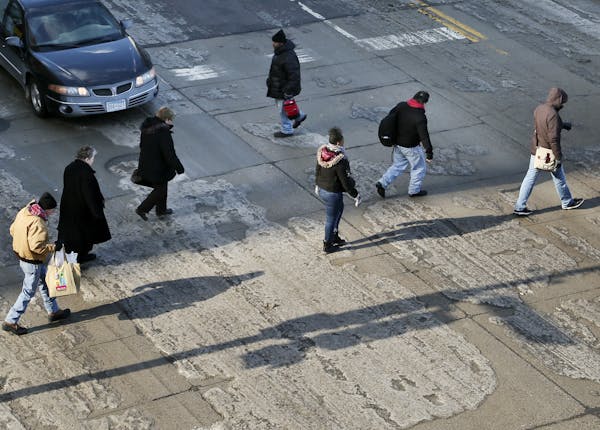 Winter has us in a rut: Pedestrians and cars have an uneven icy path to cross in downtown Minneapolis Tuesday.