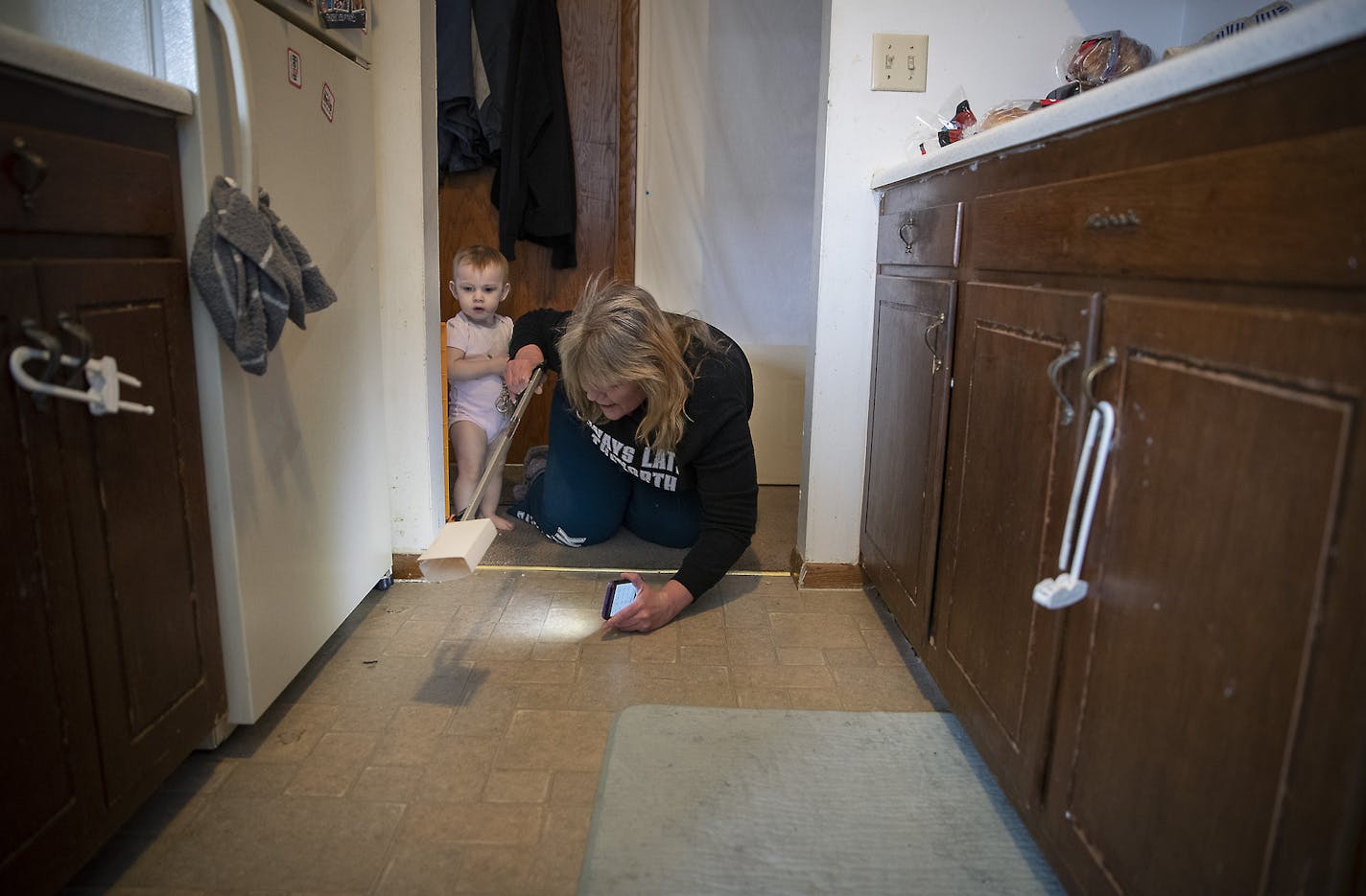 Michelle Doran checked in on her roach traps as she babysat 16-month-old Maddielynn, cq, in her 1960s' era apartment complex, Wednesday, January 29, 2020 in New Brighton, MN. ] ELIZABETH FLORES &#x2022; liz.flores@startribune.com