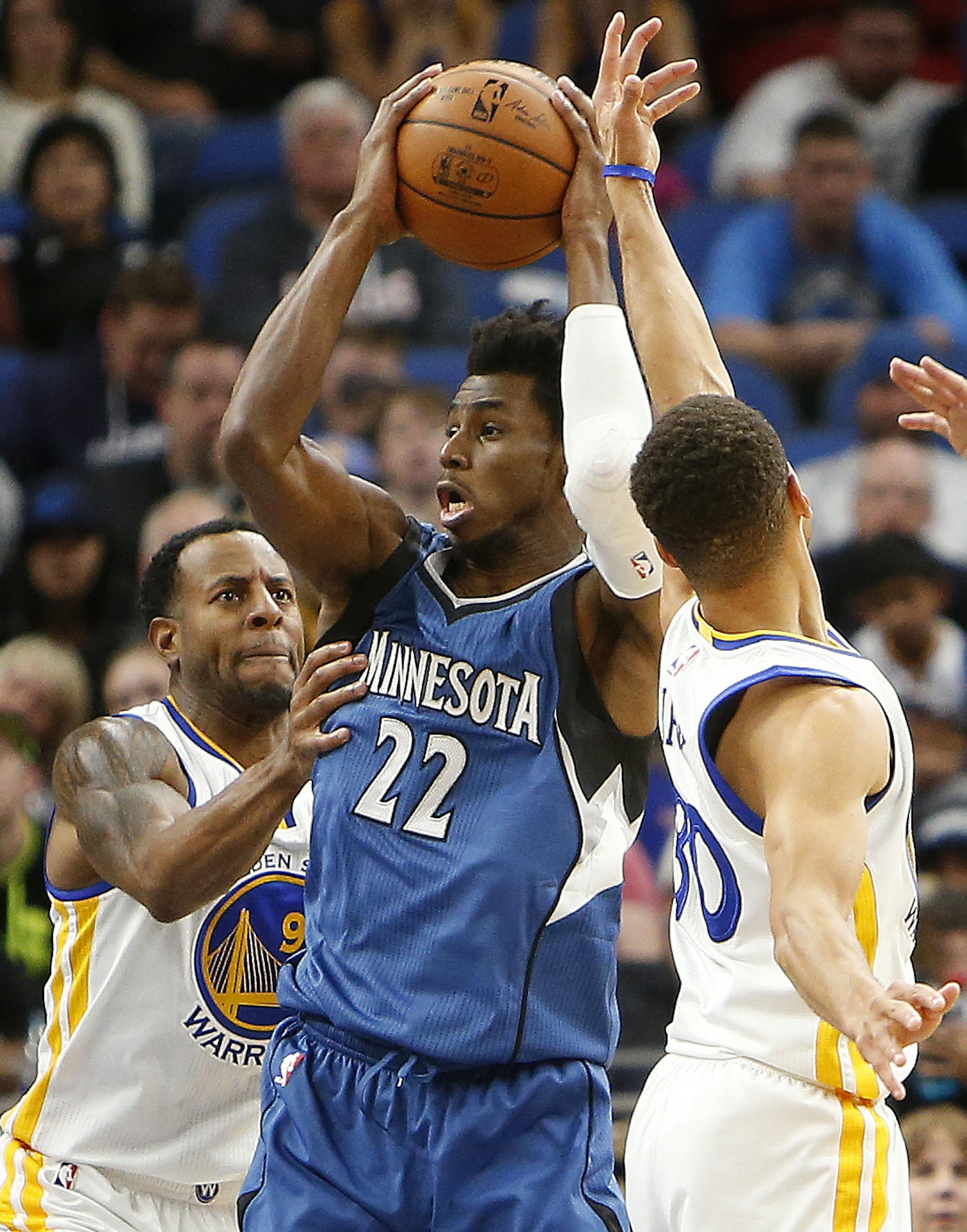 Minnesota Timberwolves forward Andrew Wiggins (22) looks to pass the ball against Golden State Warriors guards Andre Iguodala, left, and Stephen Curry, right, in the second half of an NBA basketball game Sunday, Dec. 11, 2016, in Minneapolis. Golden State won 116-108. (AP Photo/Stacy Bengs)