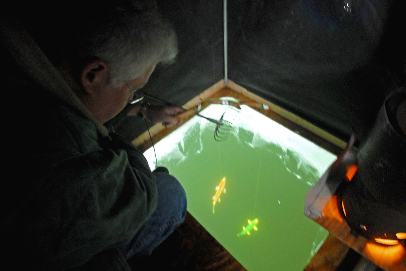 Dennis Anderson &#x2022; danderson@startribune.com ... Jan. 2007 ... Kirk Schnitker hovers over a hole in the ice, warmed by a propane heater, watching his decoys. Sometimes fish dart into the holes and attack the decoys before a spear can be thrown. Other times the fish enter slowly, giving the spearer and opportunity to make a throw. // spear fishing, spearfishing, spearing fish // ORG XMIT: MIN2015022313154822