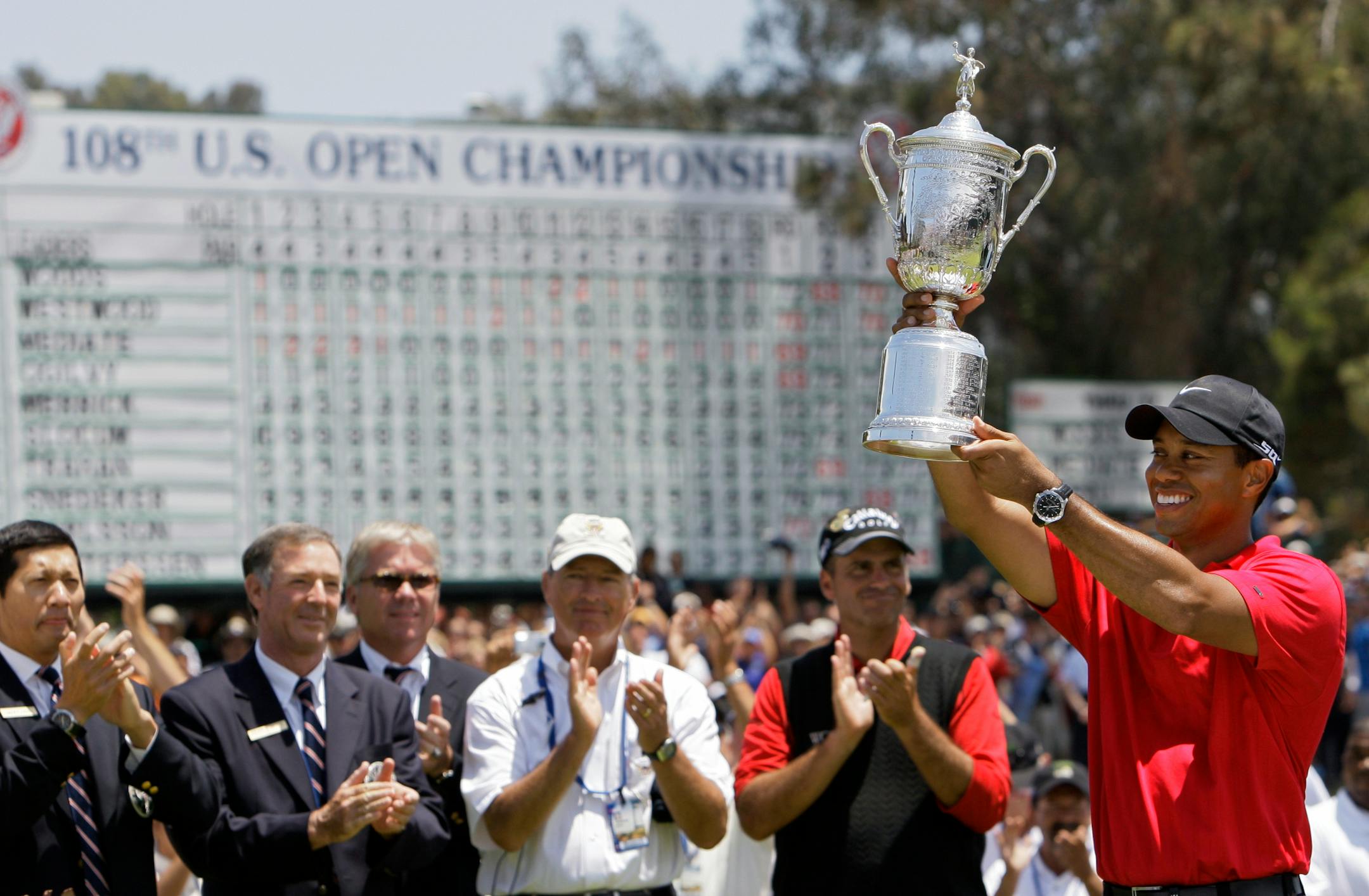 Tiger Woods held up his third U.S. Open championship trophy after defeating Rocco Mediate (just left of Woods) in a 19-hole playoff Monday at Torrey Pines Golf Course. Woods needed to birdie the 18th hole to force an extra hole, then won the title with a par.