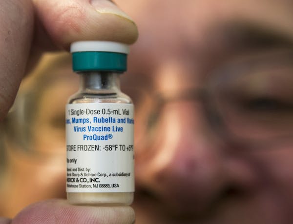 A pediatrician holds a dose of the measles-mumps-rubella (MMR) vaccine.