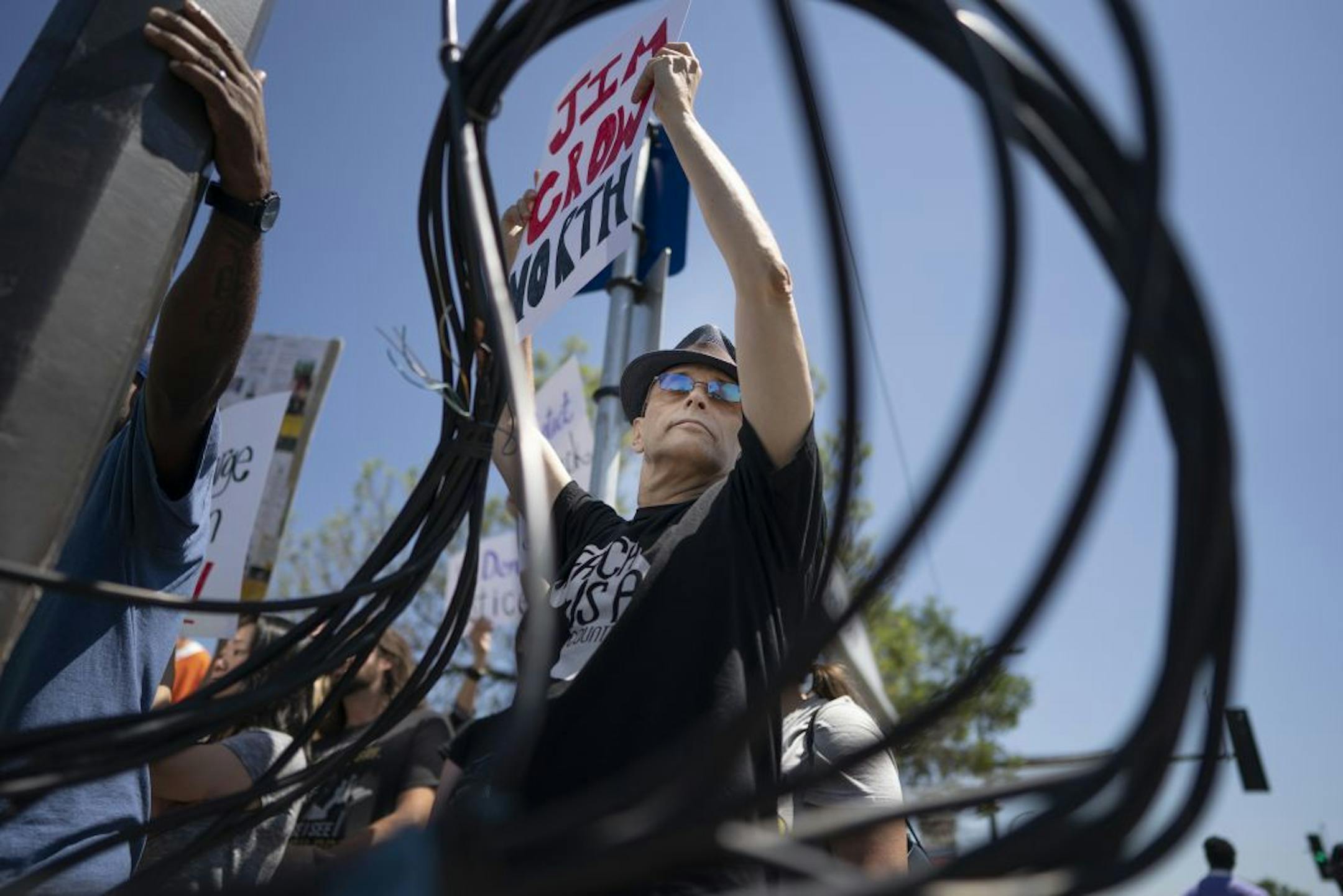Keith McCarron held a protest sign between the twisted wires left over from scene were George Jensen 83, of Champlin driver of a van that plowed in to a bus shelter on Broadway Avenue N, near Lyndale Avenue Thursday July,11 2019 in Minneapolis, MN.