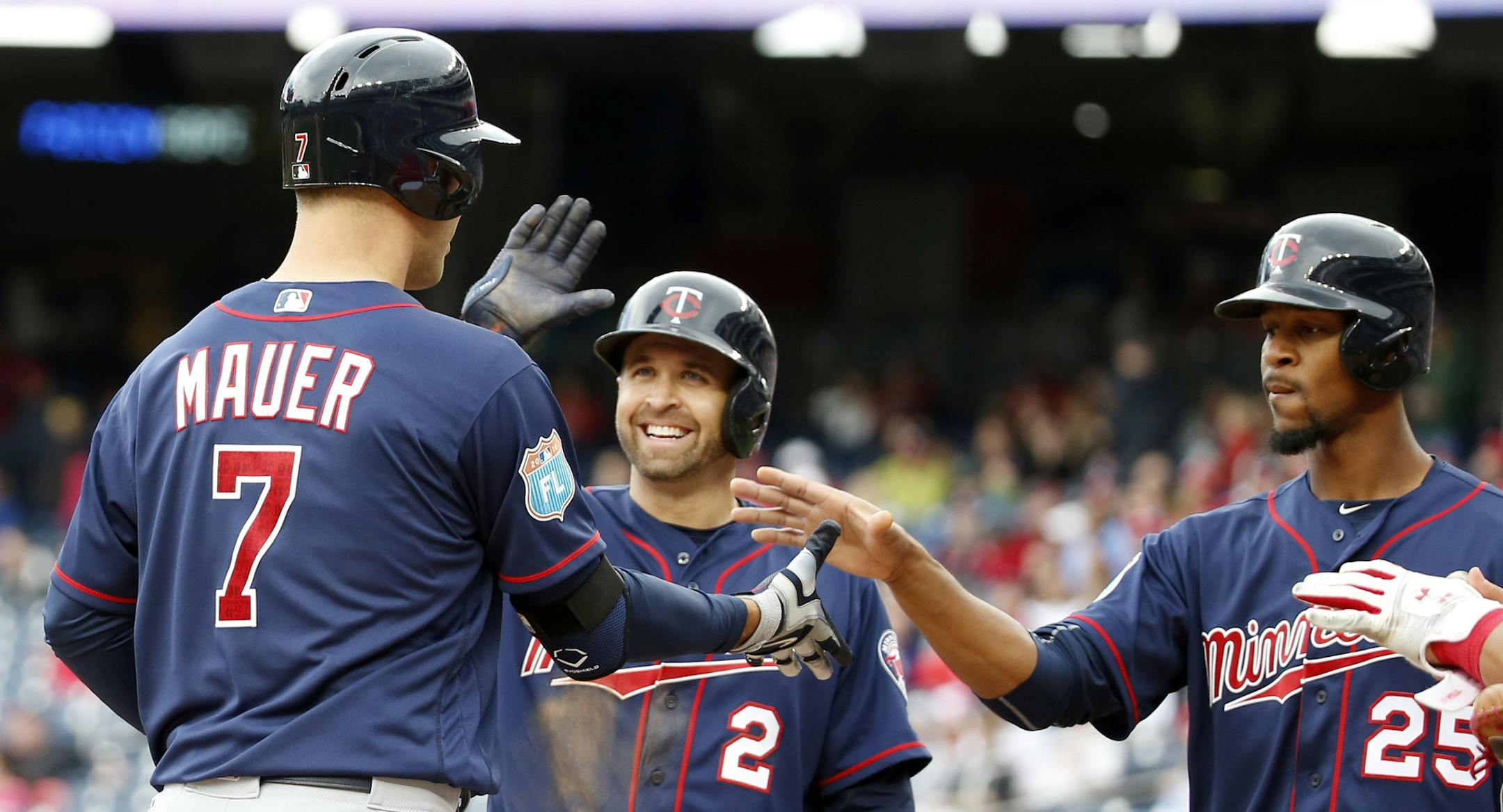 Minnesota Twins' Joe Mauer (7) celebrates knocking in Brian Dozier (2) and Byron Buxton (25) with a three-run home run during the third inning of an exhibition baseball game against the Washington Nationals at Nationals Park, Saturday, April 2, 2016, in Washington. (AP Photo/Alex Brandon)