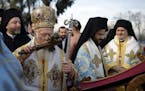 Ecumenical Patriarch Bartholomew I, the spiritual leader of the world's Orthodox Christians, kisses a wooden cross before throwing it toward swimmers 