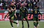 Portland Timbers defender Larrys Mabiala, left, is mobbed by teammates after scoring a goal during the first half against Minnesota United