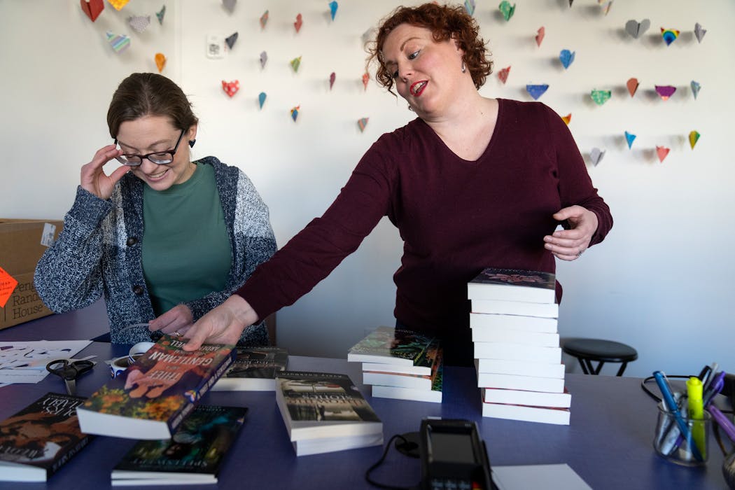 Caitlin O'Neil, left, and Lauren Richards, co-owners of romance bookstore Tropes & Trifles, organize books inside their bookstore in Minneapolis.