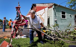 Patti Manley, 69, moves a shredded American flag as she gathers branches from the backyard of her mother's home on Morningdale Place in Mehlville, Mo.