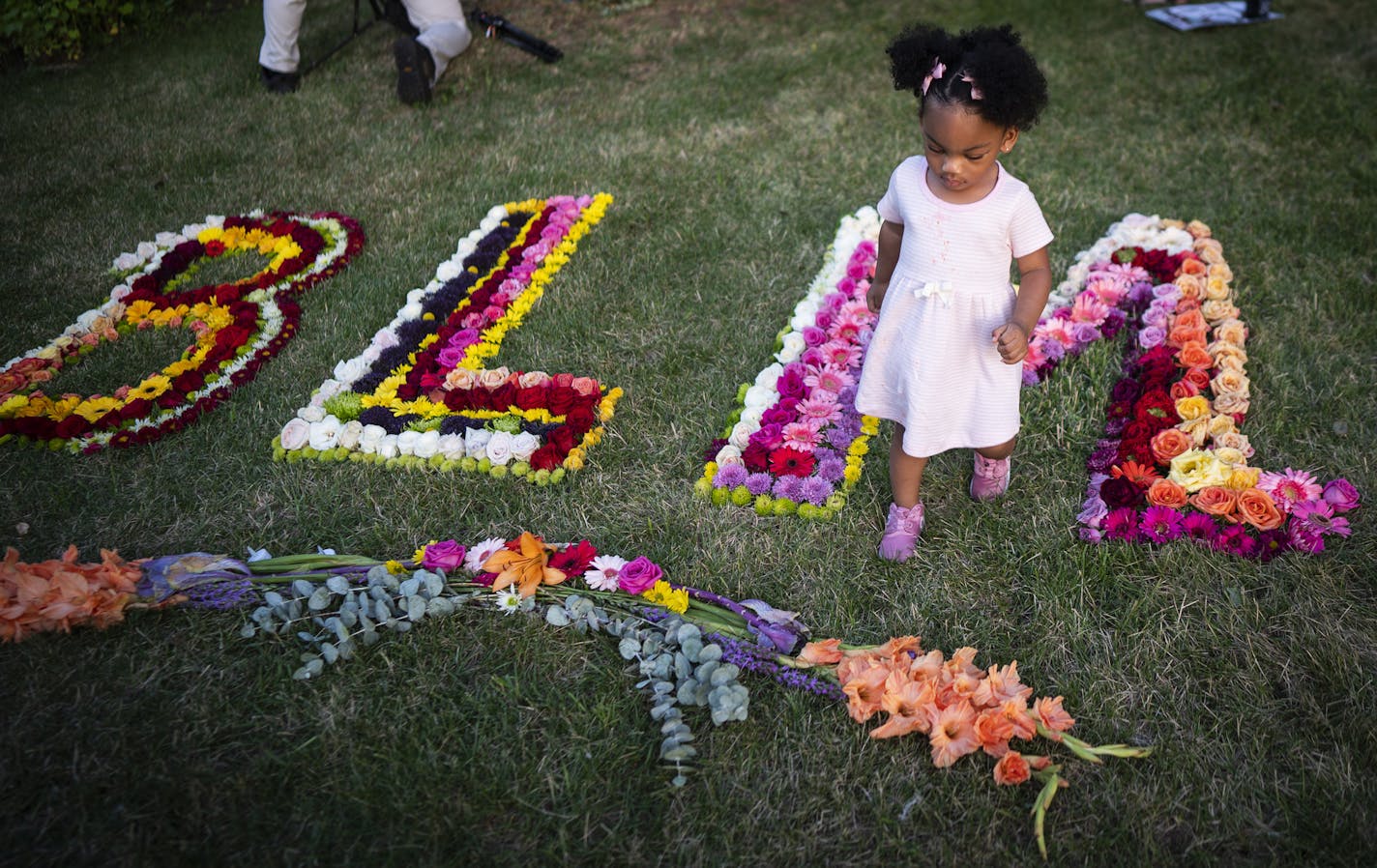 A girl walks among a flower display spelling BLM, for Black Lives Matter, at the Philando Castile memorial Tuesday, July 6, 2020, in Falcon Heights, Minn. Castile was fatally shot four years ago during a traffic stop by a police officer from St. Anthony Village. (Leila Navidi/Star Tribune via AP)