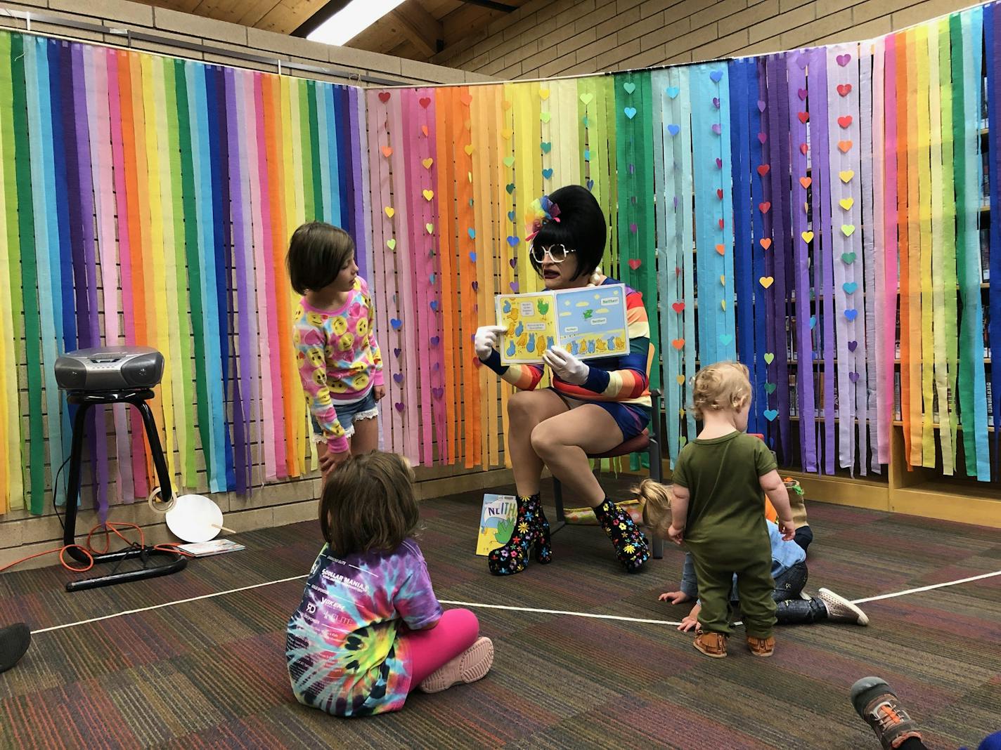 Miss Richfield 1981 pauses to let children study the pages of "Neither," one of the featured books at Saturday's Stories Together with Drag Performers at the Augsburg Park Library in Richfield.