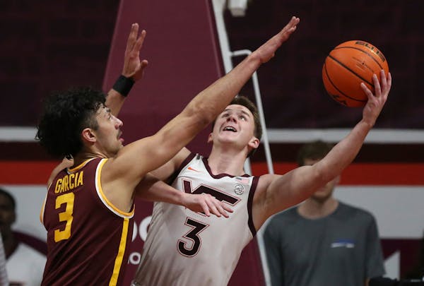 Virginia Tech's Sean Pedulla (3) scores from underneath the basket while guarded by Minnesota's Dawson Garcia (3) in the first half of an NCAA college
