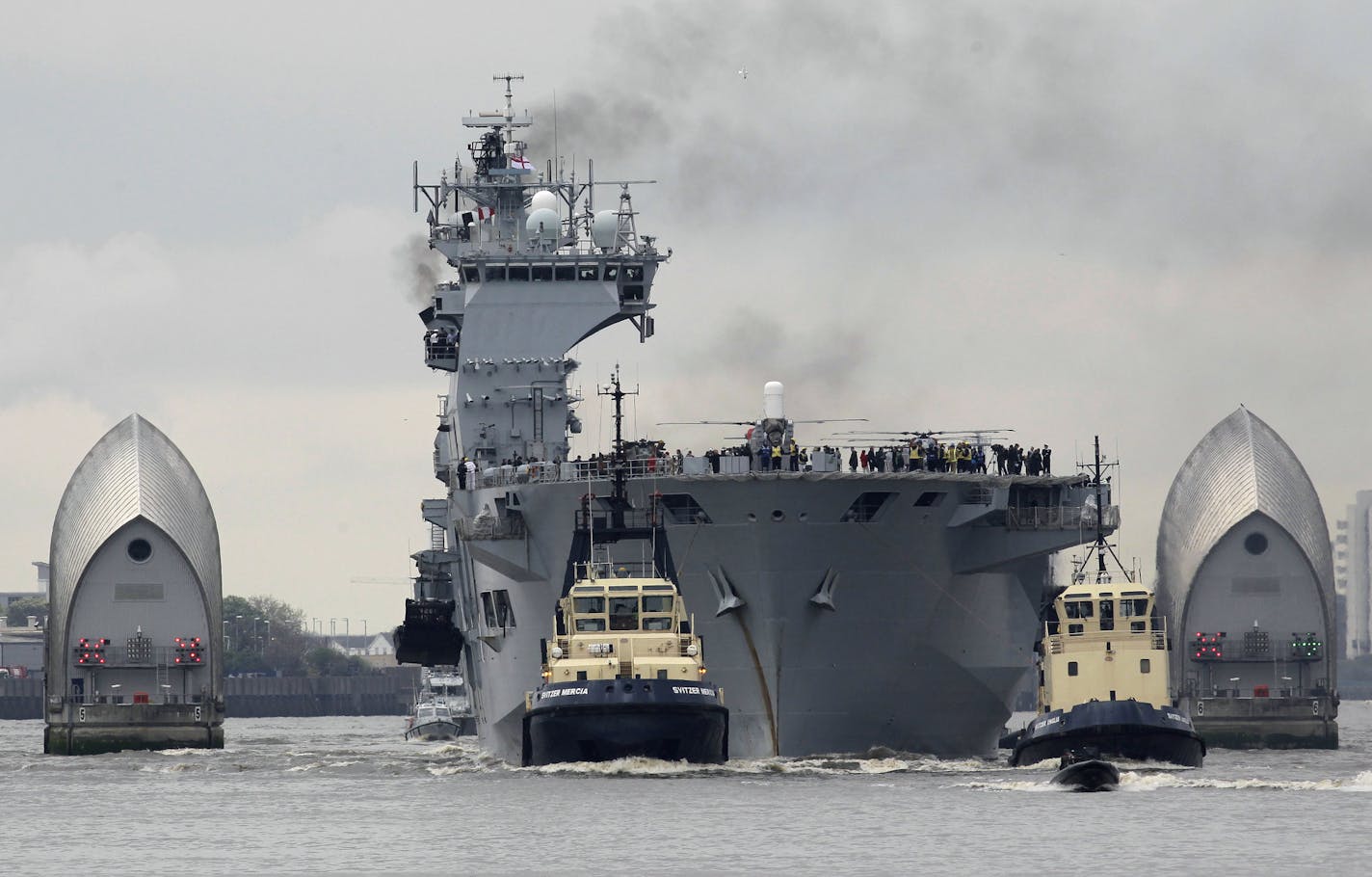 Royal Navy helicopters carrier HMS Ocean sails through the Thames Barrier on the River Thames in London to dock at Greenwich as part of London 2012 Olympic preparation security exercise, Friday, May 4, 2012. The HMS Ocean forms part of a co-ordinated defence against possible threats to the London 2012 Olympic games, involving all three British armed services. (AP Photo/Sang Tan)