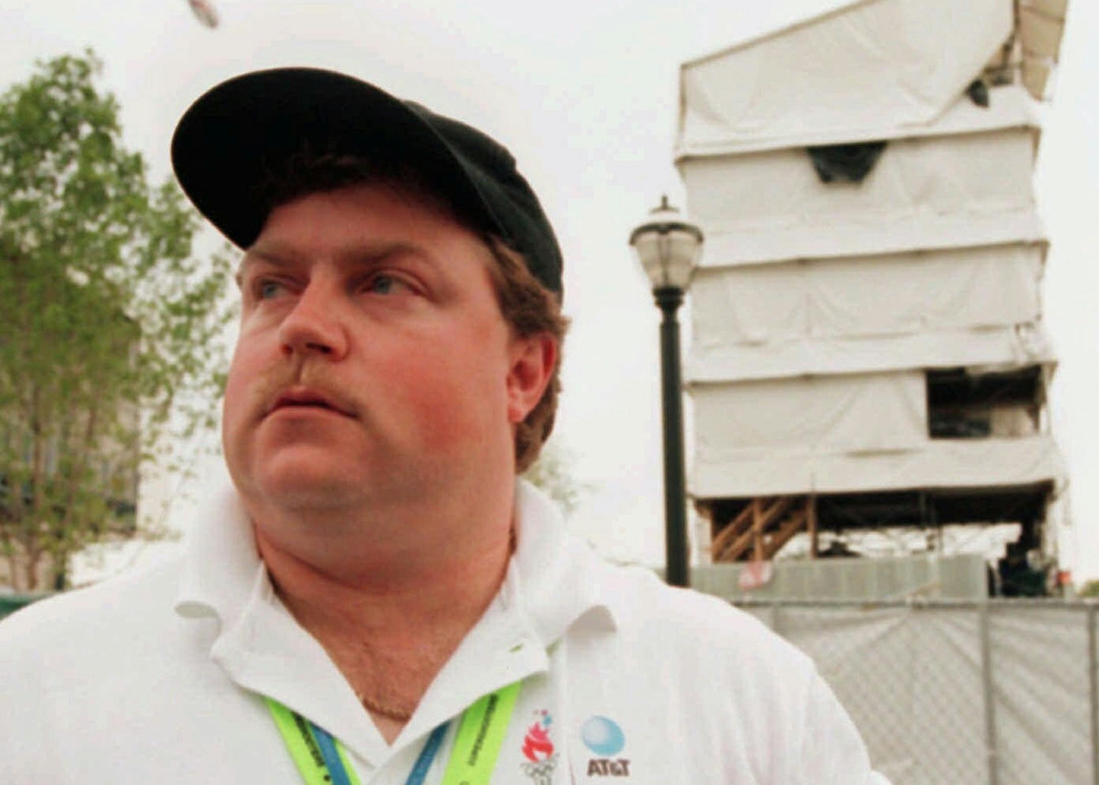 FILE- In this July 28, 1996, file photo, security guard Richard Jewell poses across from the tower where he found a bomb and warned visitors at Centennial Olympic Park in Atlanta. When a bomb exploded in a downtown Atlanta park midway through the 1996 Olympics, it set news reporters and law enforcement on a collision course that upended the life of a security guard, turning him from hero to villain overnight. Now, more than 20 years later, a recent book and upcoming movie explore Jewell's ordeal