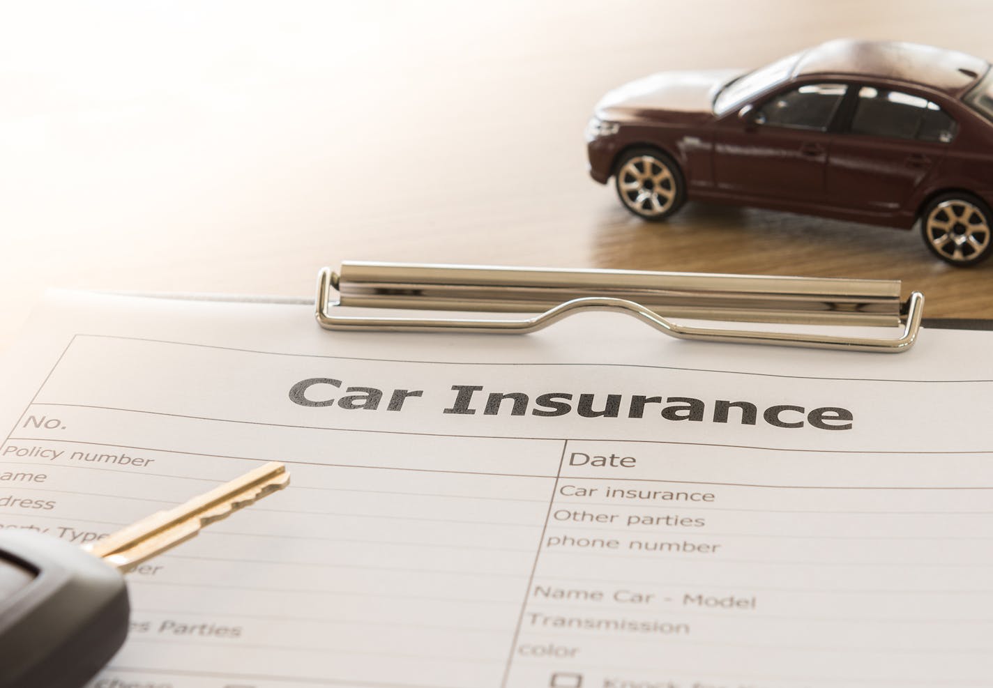 car insurance application form with car model and key remote on desk.