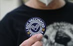 A woman holds up a sticker after getting her third dose of the COVID-19 vaccine at a clinic in Pasadena, California.