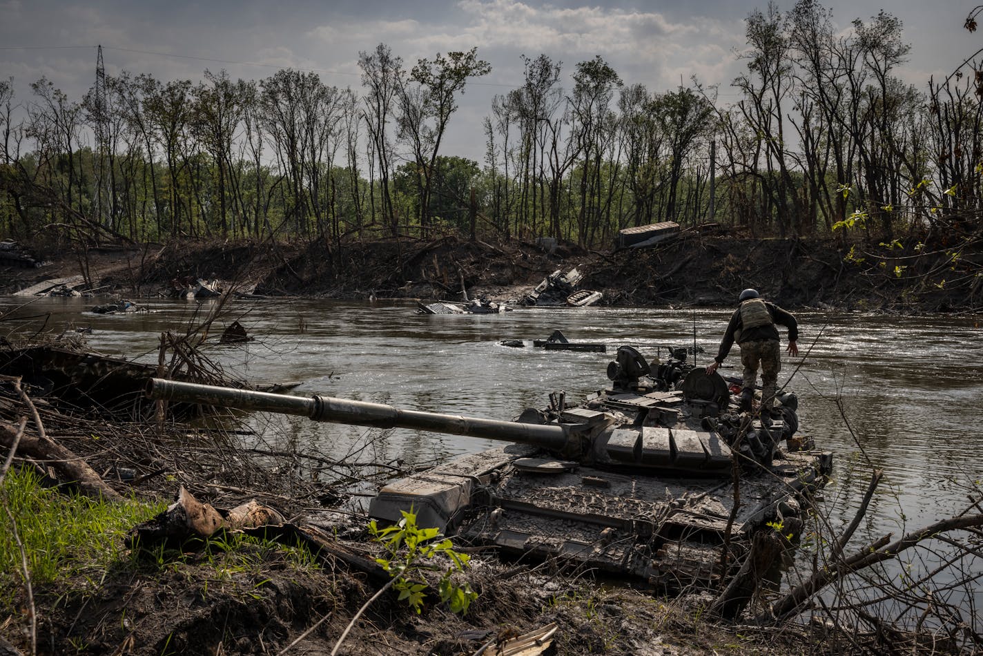 FILE Ñ A Ukrainian soldier tries to salvage a heavy machine gun from an abandoned Russian tank in the Seversky Donets River near Sievierodonetsk, Ukraine, on Wednesday, May 24, 2022. A New York Times investigation based on interviews, intercepts, documents and secret battle plans shows how a Òwalk in the parkÓ became a catastrophe for Russia. (Ivor Prickett/The New York Times)