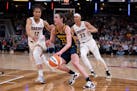 Indiana Fever's Caitlin Clark (22) goes to the basket against Atlanta Dream's Nia Coffey (12) and Aerial Powers (23) during the second half of a WNBA 