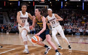 Indiana Fever's Caitlin Clark (22) goes to the basket against Atlanta Dream's Nia Coffey (12) and Aerial Powers (23) during the second half of a WNBA