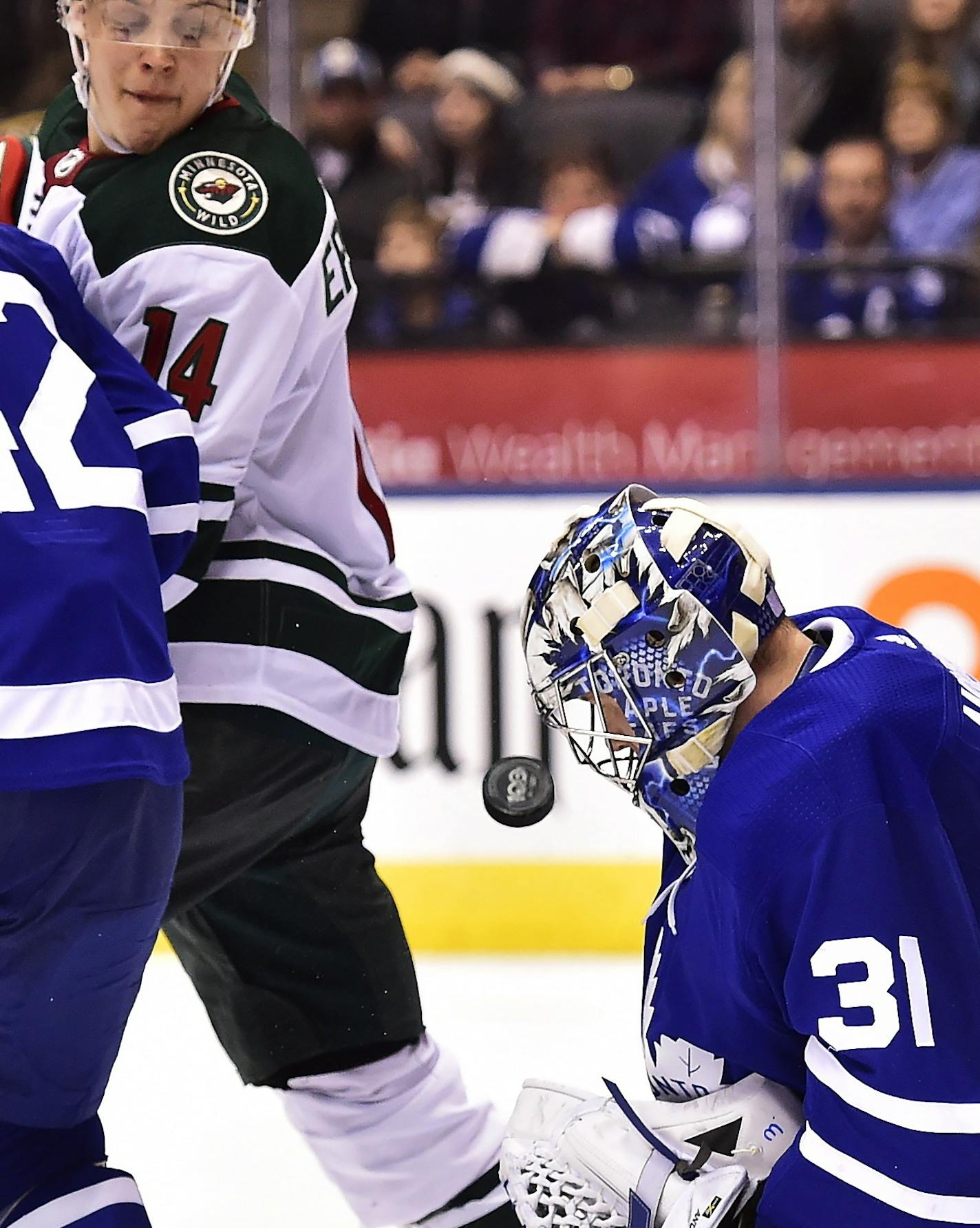 Toronto Maple Leafs goalie Frederik Andersen (31) makes a save near teammate Tyler Bozak (42) and Minnesota Wild center Joel Eriksson Ek (14) during the third period of an NHL hockey game Wednesday, Nov. 8, 2017, in Toronto. (Frank Gunn/The Canadian Press via AP)