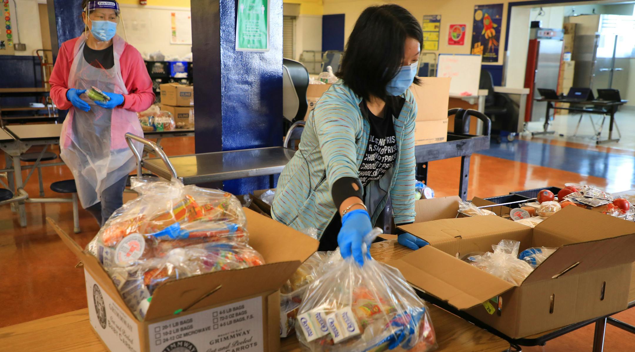 Wendy Li, left, and Rachel Huang pack meals for students to pick up on the first day of distance learning classes Sankofa United Elementary school in Oakland, Calif., Monday, Aug. 10, 2020. (Jim Wilson/The New York Times)