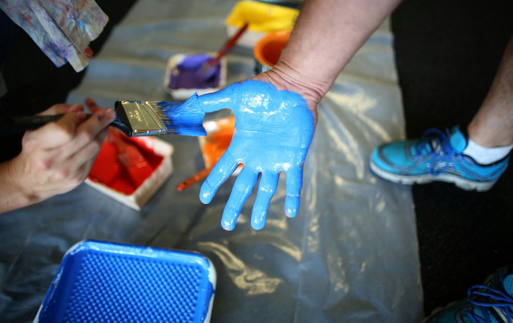 Heather Hoffman painted the hand of another volunteer Jim Gitar before making a hand print on the wall at the entrance to the school. ] (KYNDELL HARKNESS/STAR TRIBUNE) kyndell.harkness@startribune.com During a day of "beautification" at Northport Elementary School in Brooklyn Park, Min., Tuesday, August, 19, 2014.