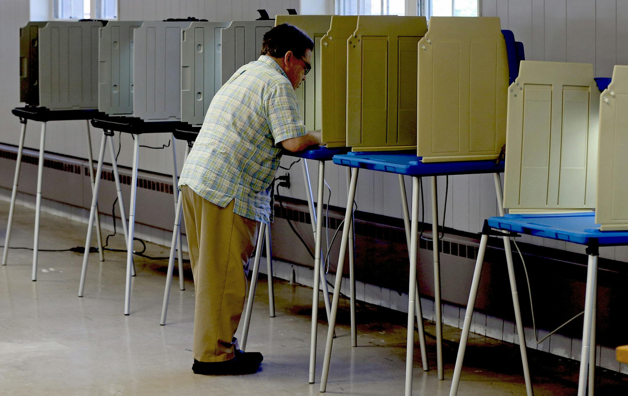 A lone voter casts his ballot at a polling place inside a south Minneapolis church, Tuesday, Aug. 12, 2014.