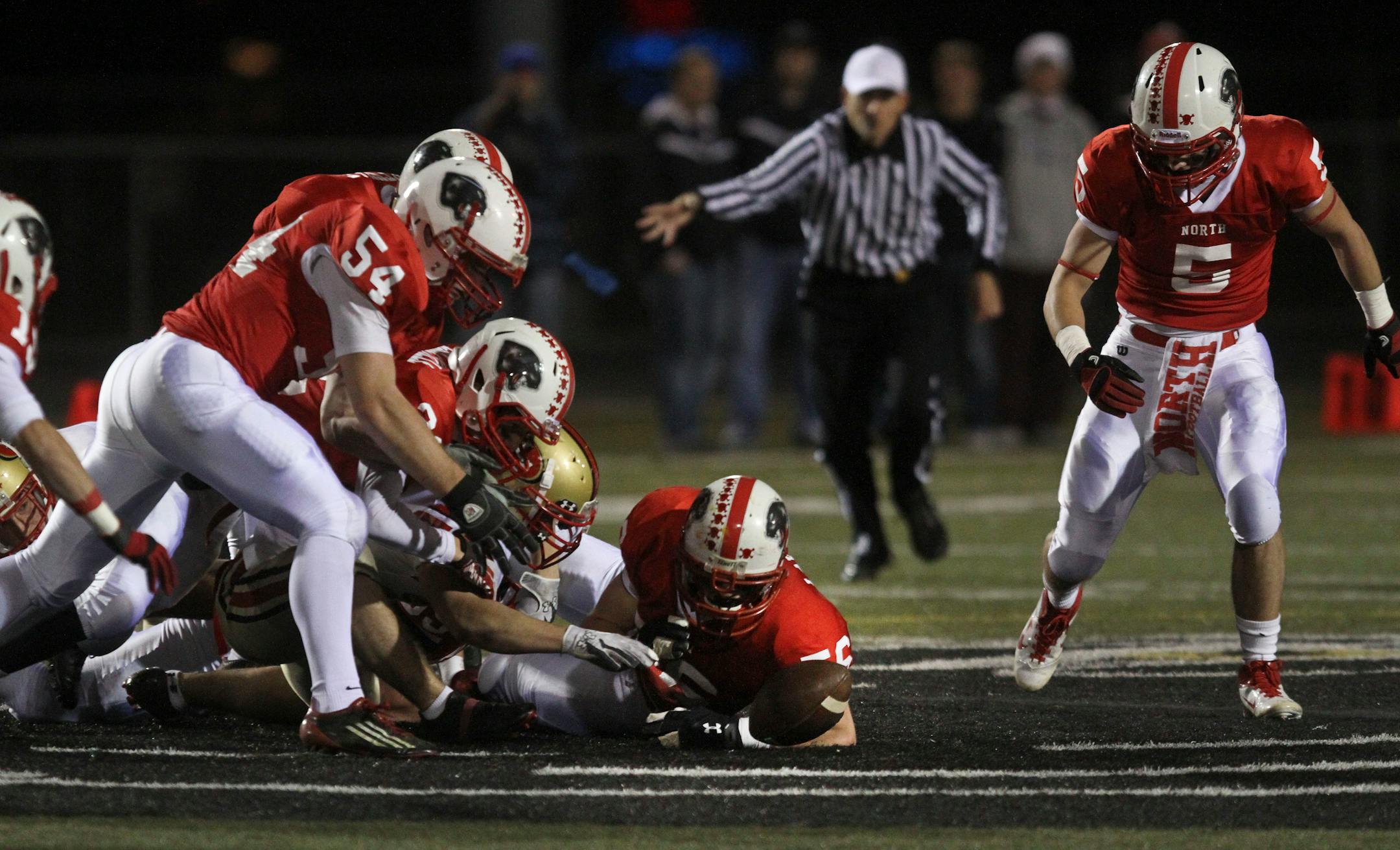 A swarm of Lakeville North defenders pursued a fumble as Lakeville South's Braden Kaufenberg tried to get it back in the first half of Saturday's playoff game.