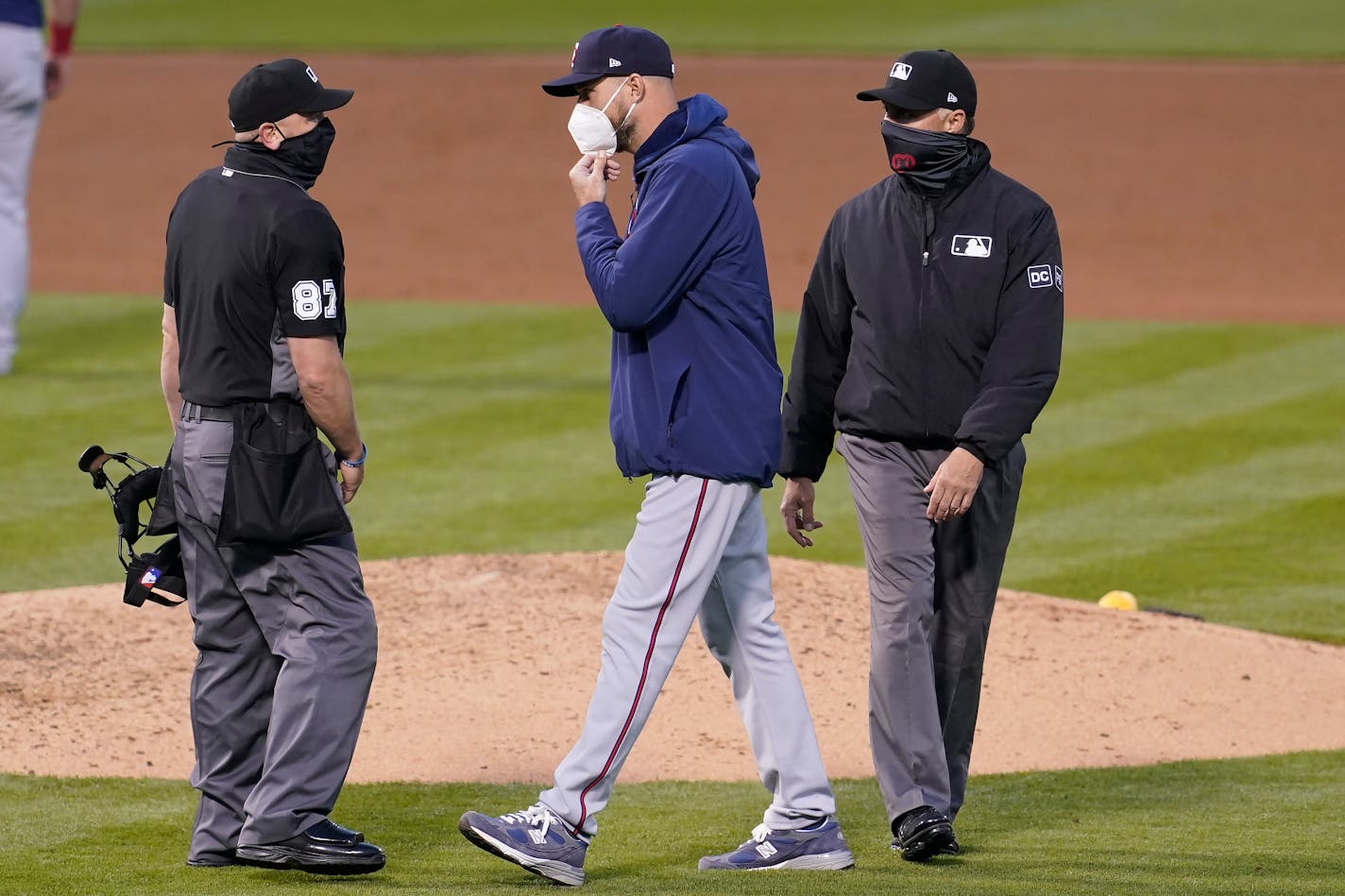 Minnesota Twins manager Rocco Baldelli, middle, talks with umpire Scott Barry (87) during the fourth inning of the second baseball game of a doubleheader between the Oakland Athletics and the Twins in Oakland, Calif., Tuesday, April 20, 2021. (AP Photo/Jeff Chiu)