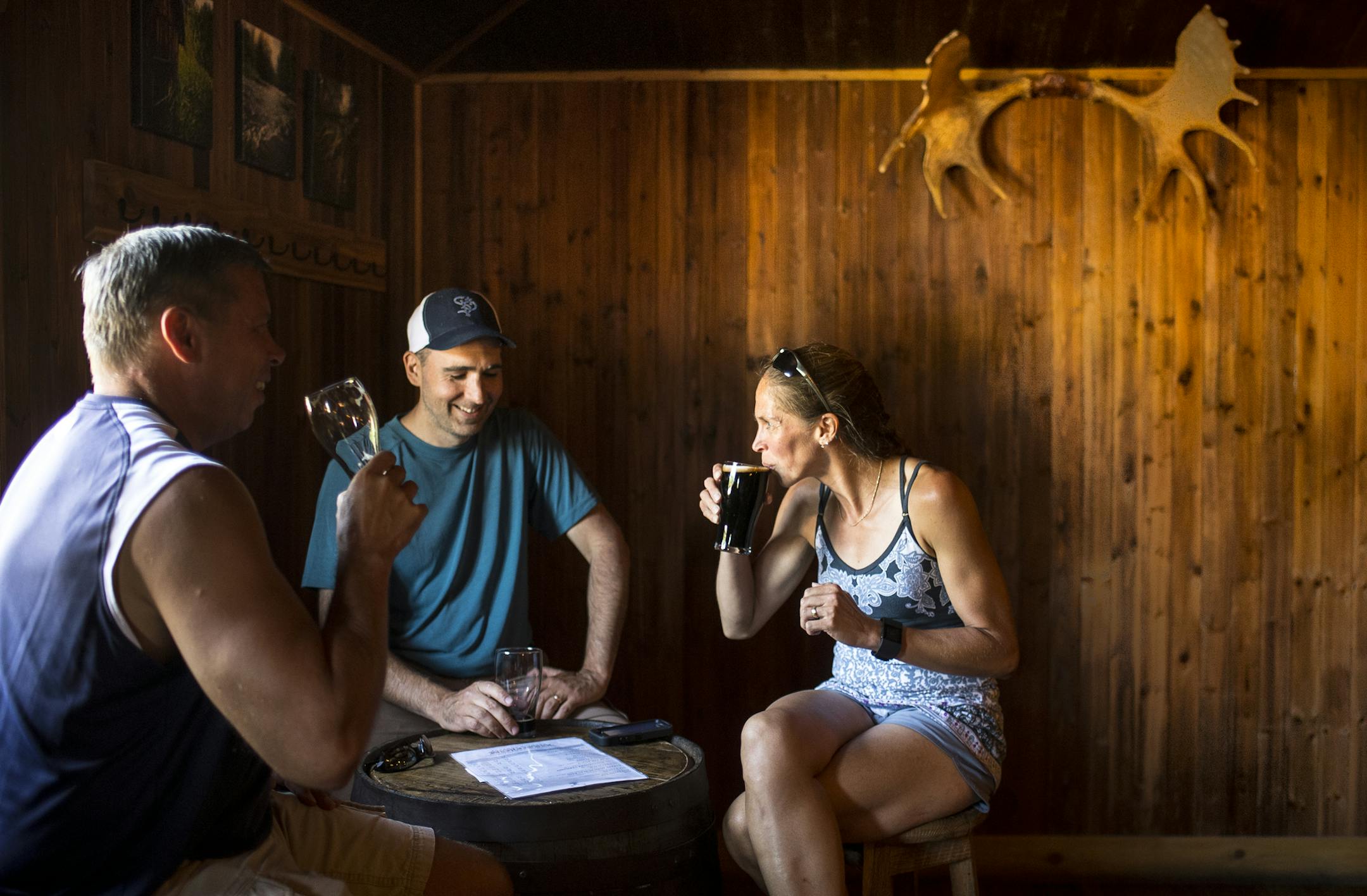 From left, Keith Paap (CQ), of Excelsior, and John and Kristen Genet, of Blaine, drank in Hammerheart Brewing's taproom Saturday. The three are drinking Dunkelwald, Hokan's Brown and Laurentian Porter respectively. ] (AARON LAVINSKY/STAR TRIBUNE) aaron.lavinsky@startribune.com Photos to accompany a feature on craft beer taprooms. Photographed Saturday, June 25, 2016 in White Bear Lake and Lino Lakes.