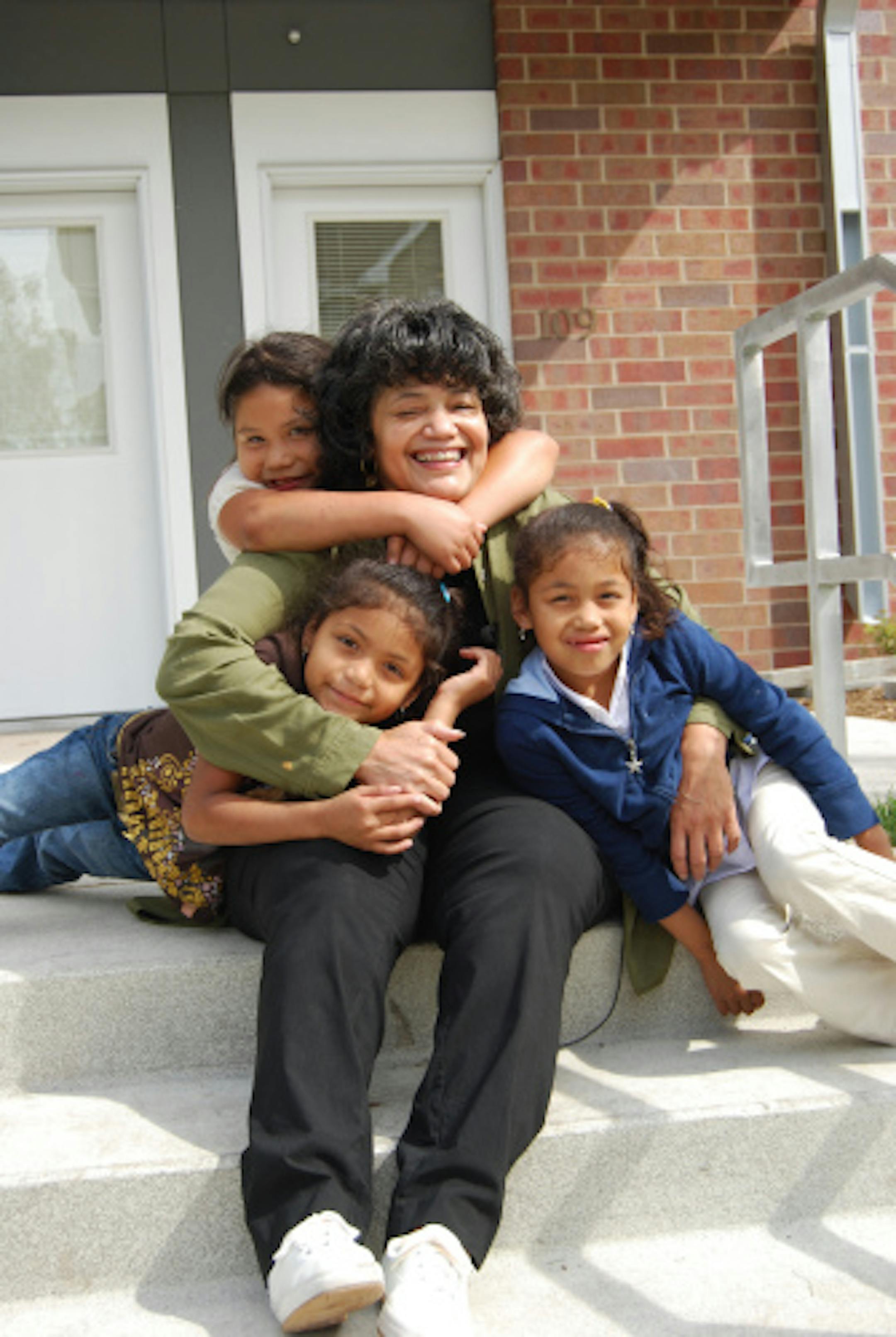 Cheryl Barney on the front step of her new home with three of the five grandchildren she is raising.