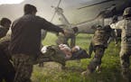 Members of Afghan's security forces carry a wounded comrade into a US Army medevac helicopter that landed on the outer perimeter of Combat Outpost Pir