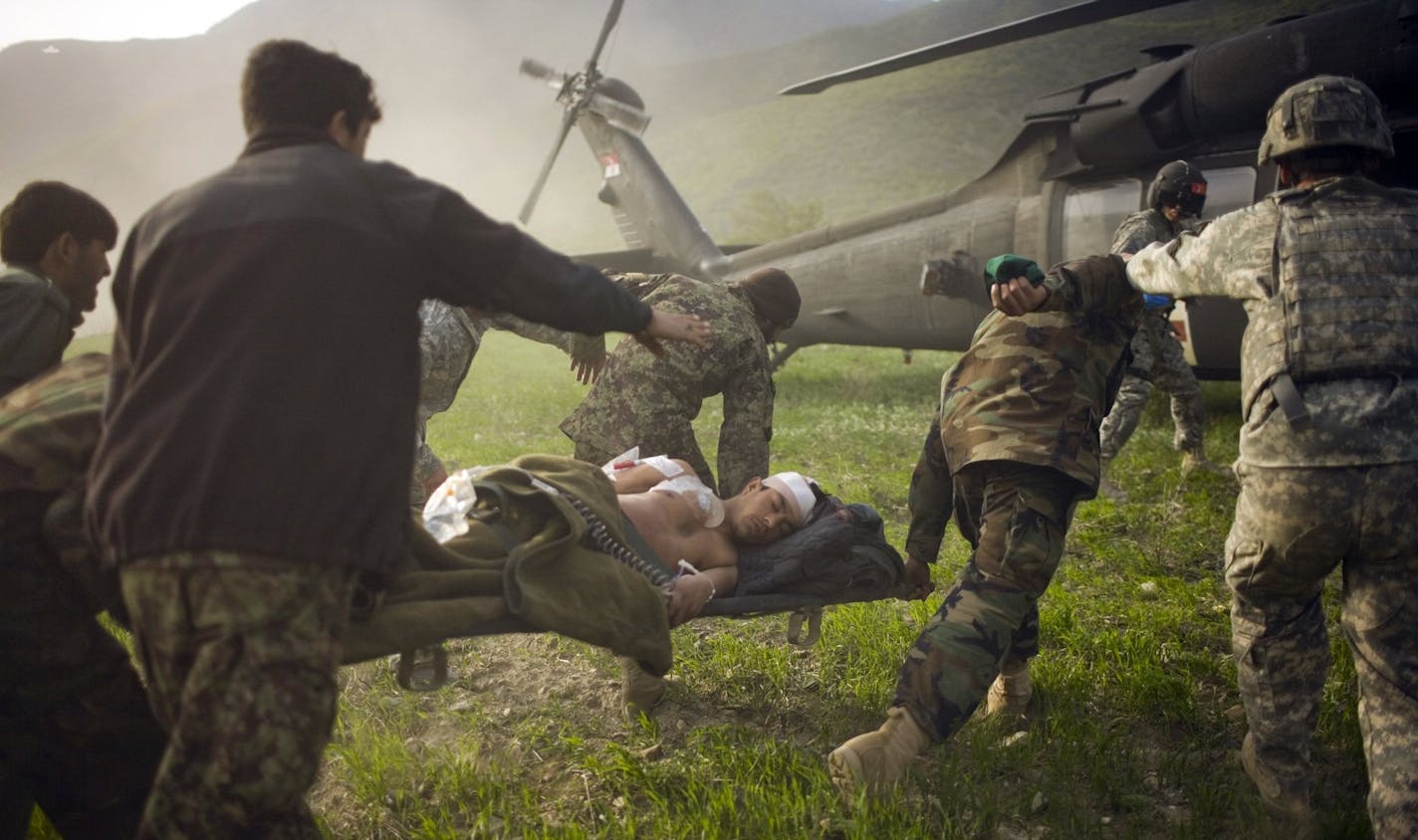 Members of Afghan's security forces carry a wounded comrade into a US Army medevac helicopter that landed on the outer perimeter of Combat Outpost Pirtle King, near the village of Tsunek, in Afghanistan's northeast Kunar Province, March 11, 2010. Two members of the Afghan security forces were injured during an ambush in the village of Zanger Bosha and were evacuated to the outpost for initial treatment. The two were then taken by helicopter to Jalalabad for further medical attention. Both Afghan