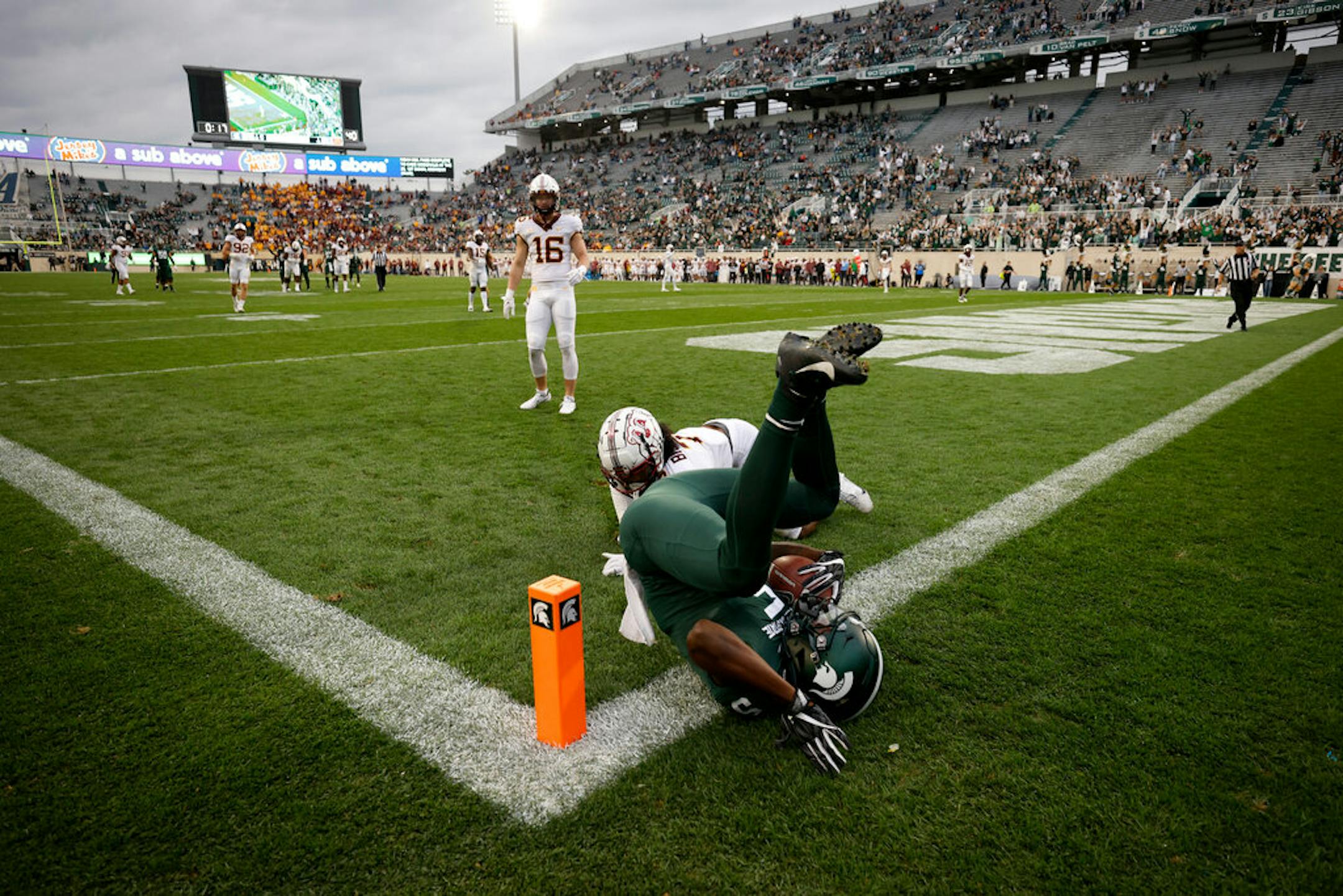 Michigan State's Germie Bernard, right, scores on a pass reception against Minnesota's Beanie Bishop during the second half of an NCAA college football game, Saturday, Sept. 24, 2022, in East Lansing, Mich. Minnesota won 34-7. (AP Photo/Al Goldis)
