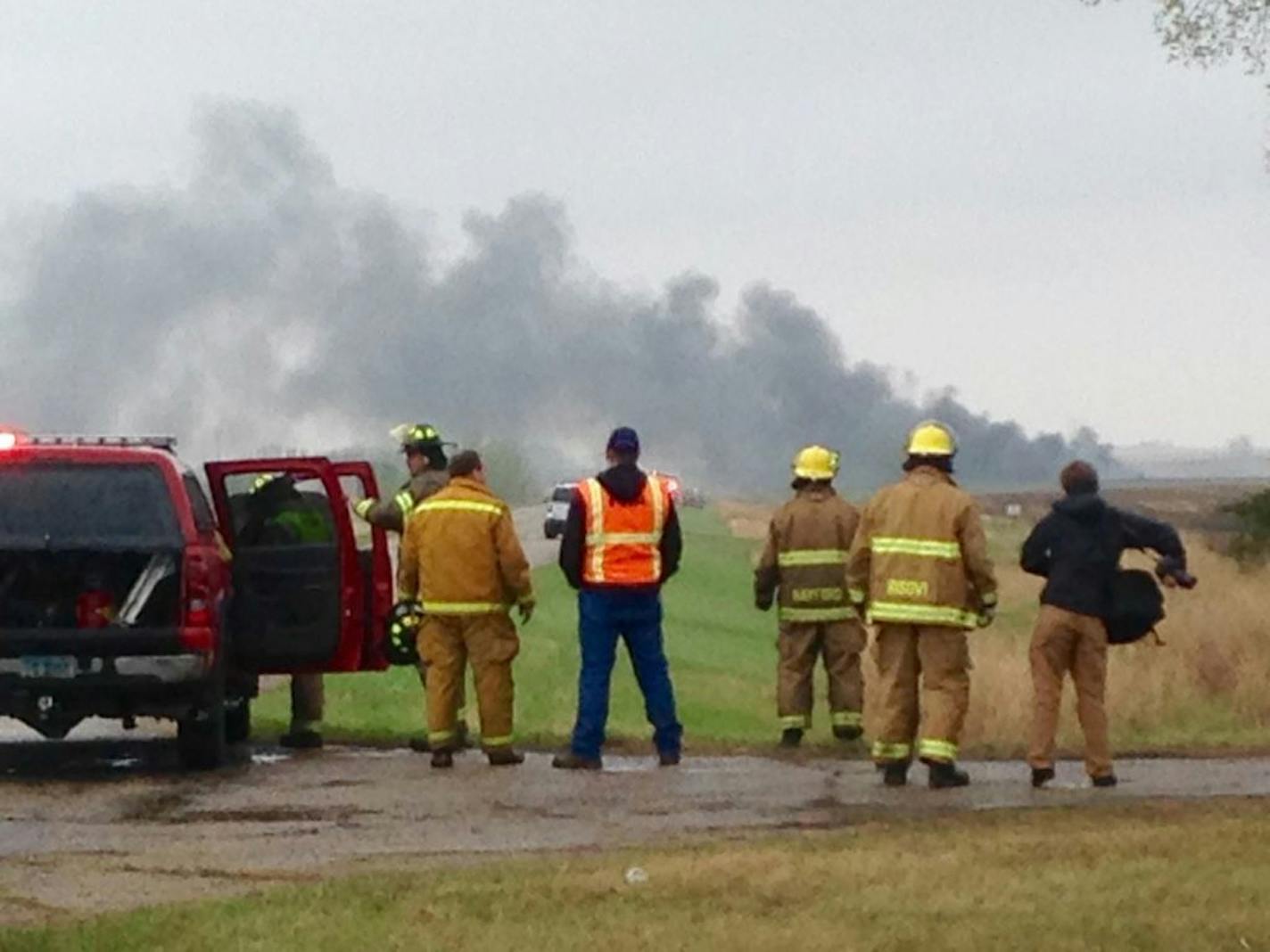 Emergency personnel watch as smoke rises in the background past a field after a BNSF Railway oil train derailed and caught fire in a rural area about two miles from Heimdal, N.D.. Wednesday, May 6, 2015. The central North Dakota town had to been evacuated due to the derailment and fire.