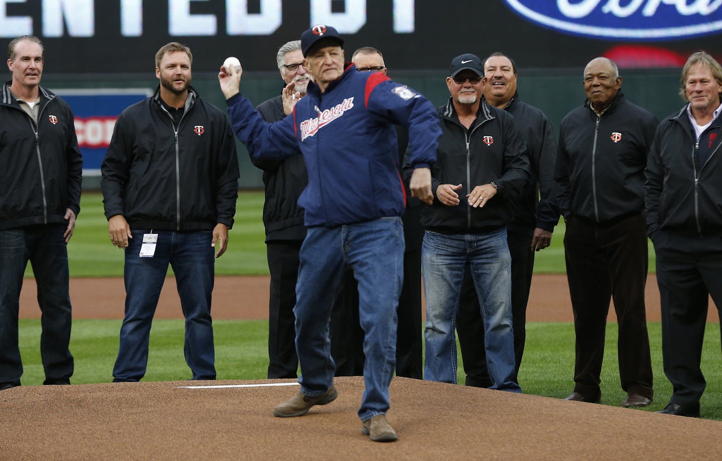 Former Minnesota Twins coach Rick Stelmaszek, center, throws out the ceremonial first pitch before the season opener baseball game against the Kansas City Royals Monday, April 3, 2017 in Minneapolis. Stelmaszek, who coached with the Twins for 32 years, is battling pancreatic cancer. (AP Photo/Jim Mone) ORG XMIT: MIN2017040319081713