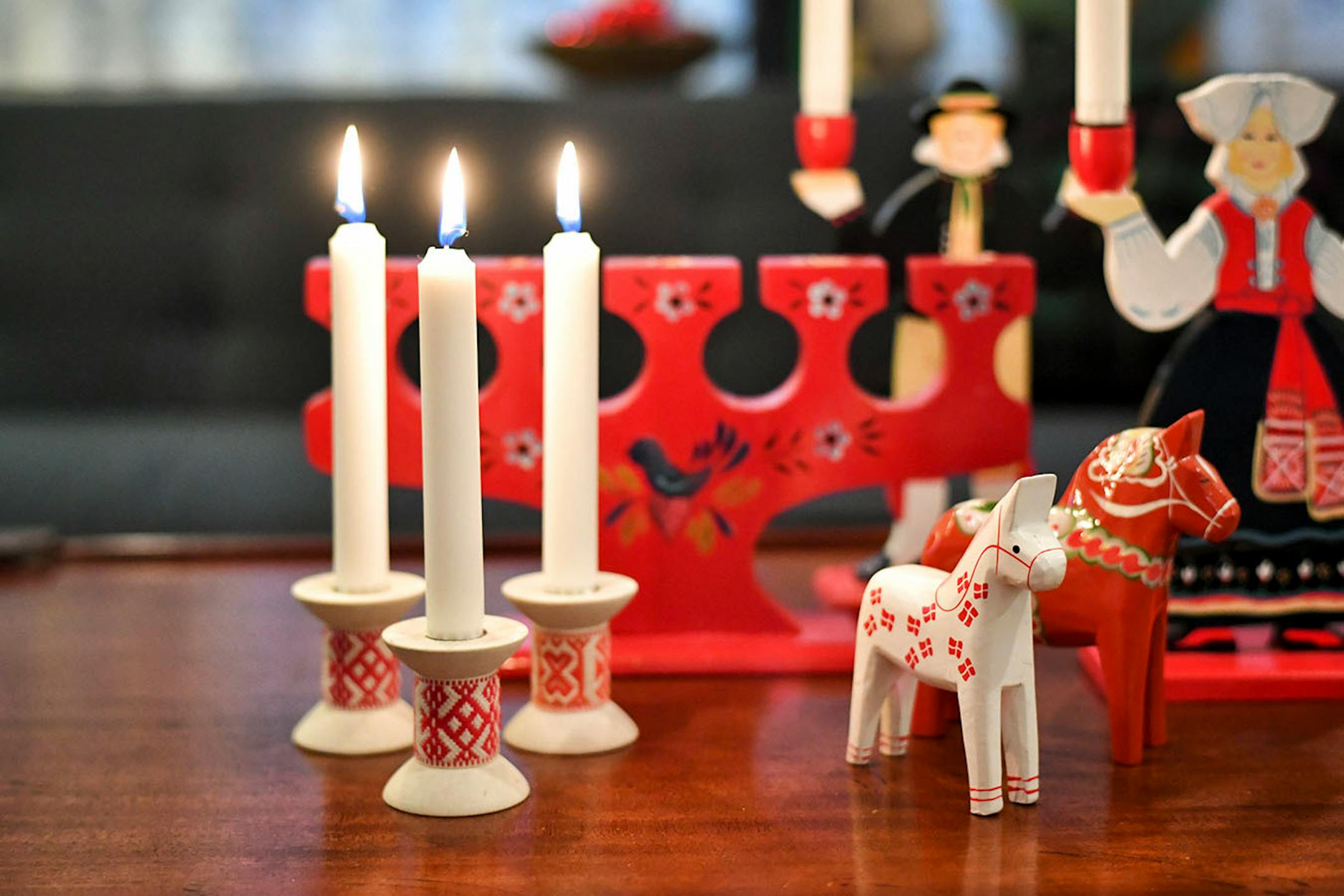 Scandia-style: An assortment of Scandinavian folk art collectibles on a vintage coffee table. Choose pieces with a similar style, for example, the Dala horses and other objects are painted wood. Add an unexpected contrasting detail, such as the green ceramic bowl from Sweden.