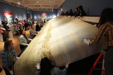 Minnesota Marine Art Museum staff, including curator Jon Swanson, left, and volunteers work to advance a 40-foot section of "A Spectacle in Motion: Th