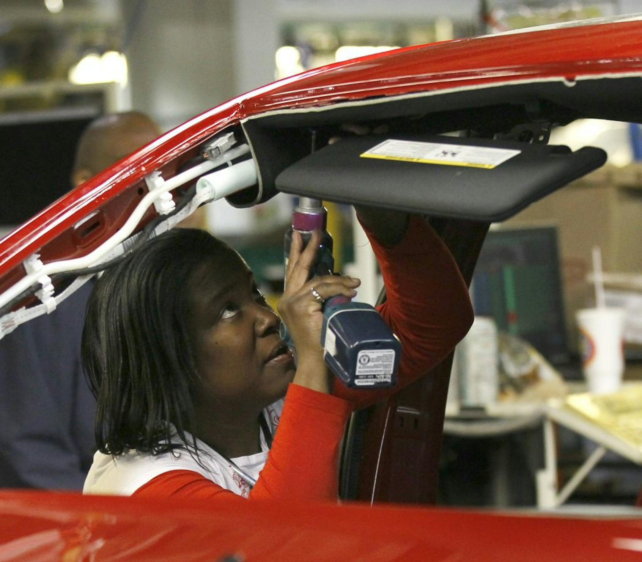An auto worker assembles parts on a Dodge Dart at the Chrysler plant Belvidere, Ill.