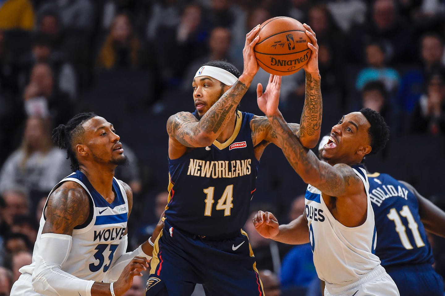 New Orleans forward Brandon Ingram grabs a rebound between Timberwolves forward Robert Covington, left, and guard Jeff Teague