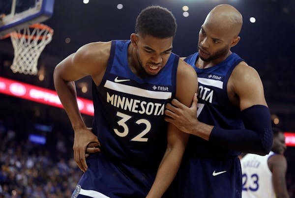 Minnesota Timberwolves' Taj Gibson, right, checks on the condition of Karl-Anthony Towns (32), who had collided with Golden State Warriors' Draymond G