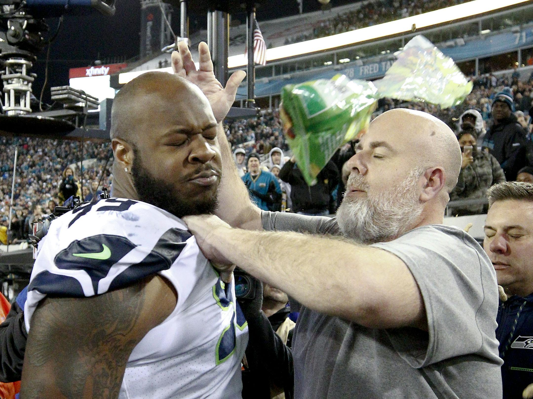Seahawks equipment manager Erik Kennedy kept defensive tackle Quinton Jefferson, left, from going into the stands after a fan after an object was thrown at him as he left the field following a game against the Jacksonville Jaguars on Sunday.