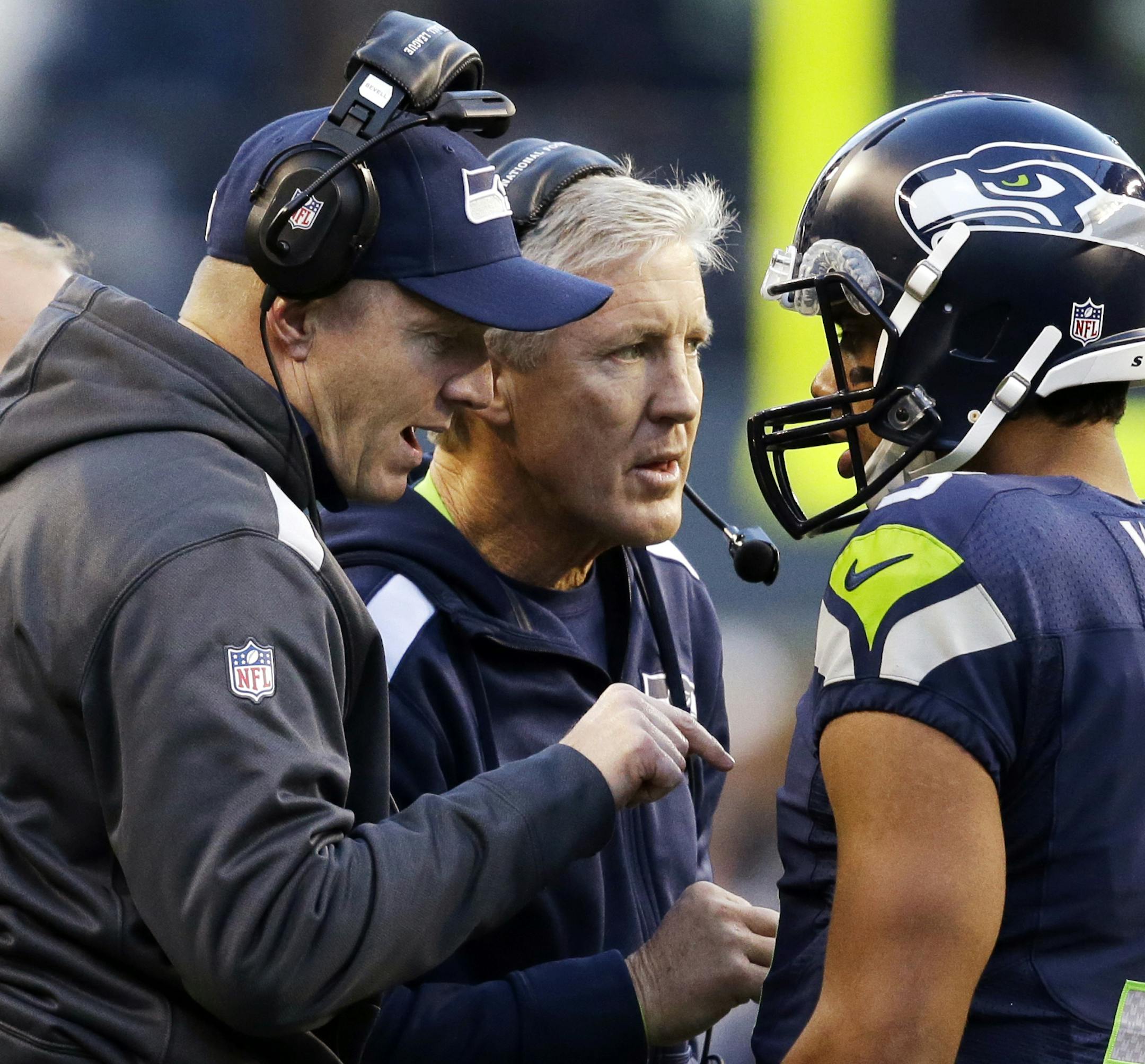 Seattle Seahawks quarterback Russell Wilson (3) talks with head coach Pete Carroll, center, and offensive coordinator Darrell Bevell before Wilson's final play against the Tampa Bay Buccaneers in overtime in an NFL football game Sunday, Nov. 3, 2013, in Seattle. The Seahawks won 27-24 on a field goal in overtime. (AP Photo/Elaine Thompson) ORG XMIT: SEA156