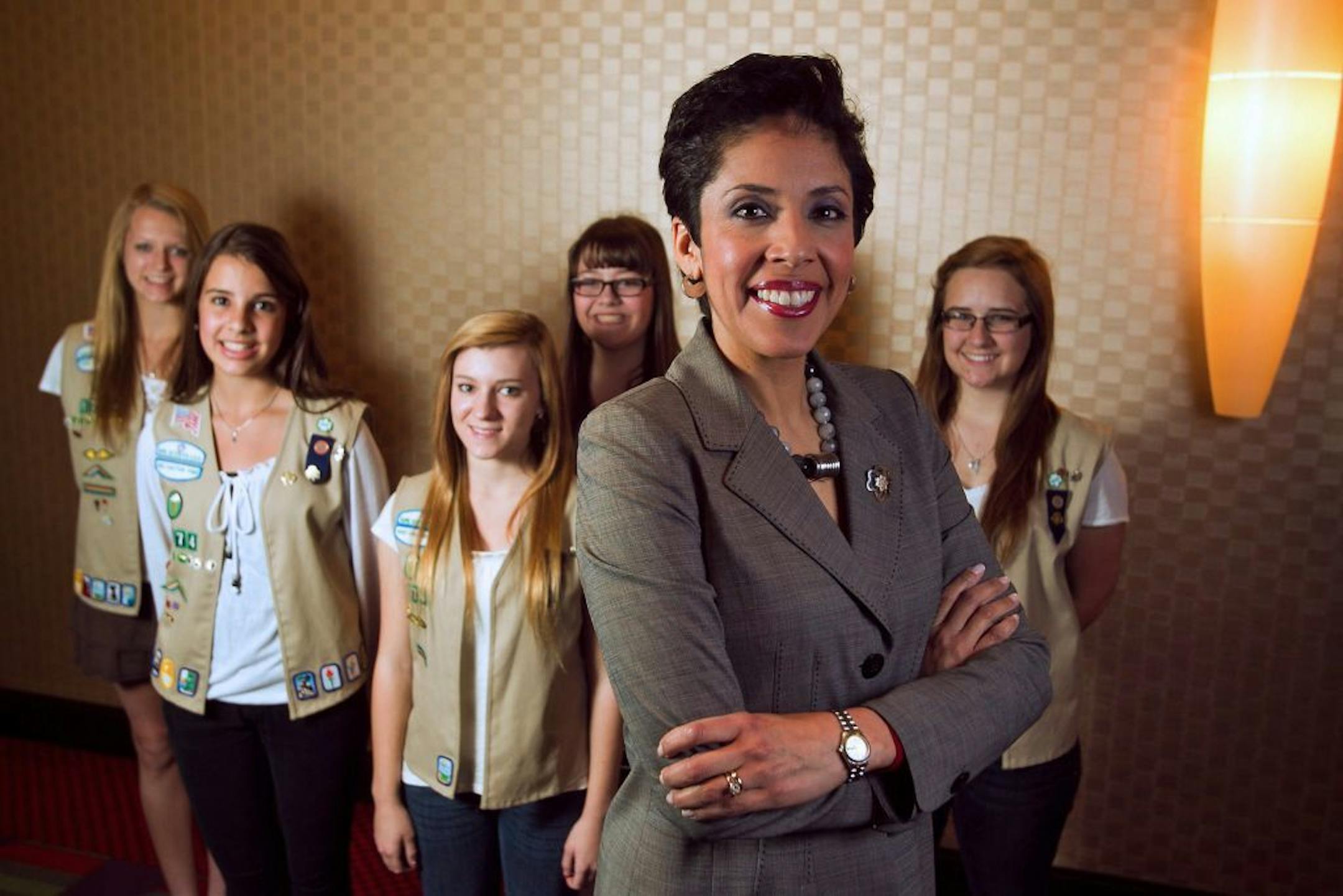 FILE - In this March 28, 2012 file photo, Girl Scouts of the USA CEO Anna Maria Chavez, foreground, stands with members of Girl Scout Troop 1774; From left are Megan Zimmerman, 17, Molly Gulden, 15, Jessica Krehbiel, 16, Shelby Johnstone, 15, and Lauren McCabe, 16, all of Shadow Mountain High School in Phoenix. Compounding the problems at the organization are tensions at GSUSA headquarters in New York, where several senior executives have quit or been ousted since Chavez took over as CEO in 2011