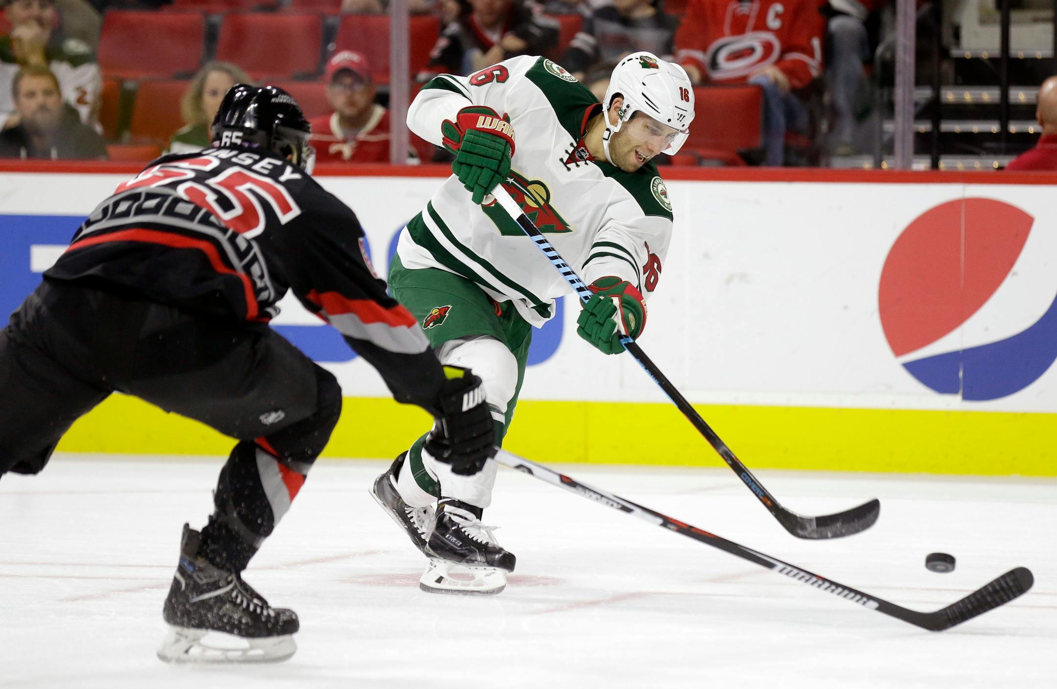 Carolina Hurricanes' Ron Hainsey, left, defends as Minnesota Wild's Jason Zucker (16) shoots.
