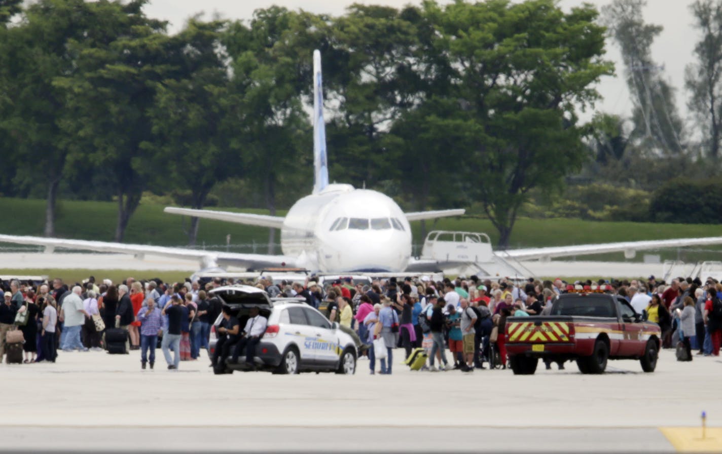 People stand on the tarmac at the Fort Lauderdale-Hollywood International Airport after a shooter opened fire inside a terminal of the airport, killing several people and wounding others before being taken into custody, Friday, Jan. 6, 2017, in Fort Lauderdale, Fla. (AP Photo/Lynne Sladky)