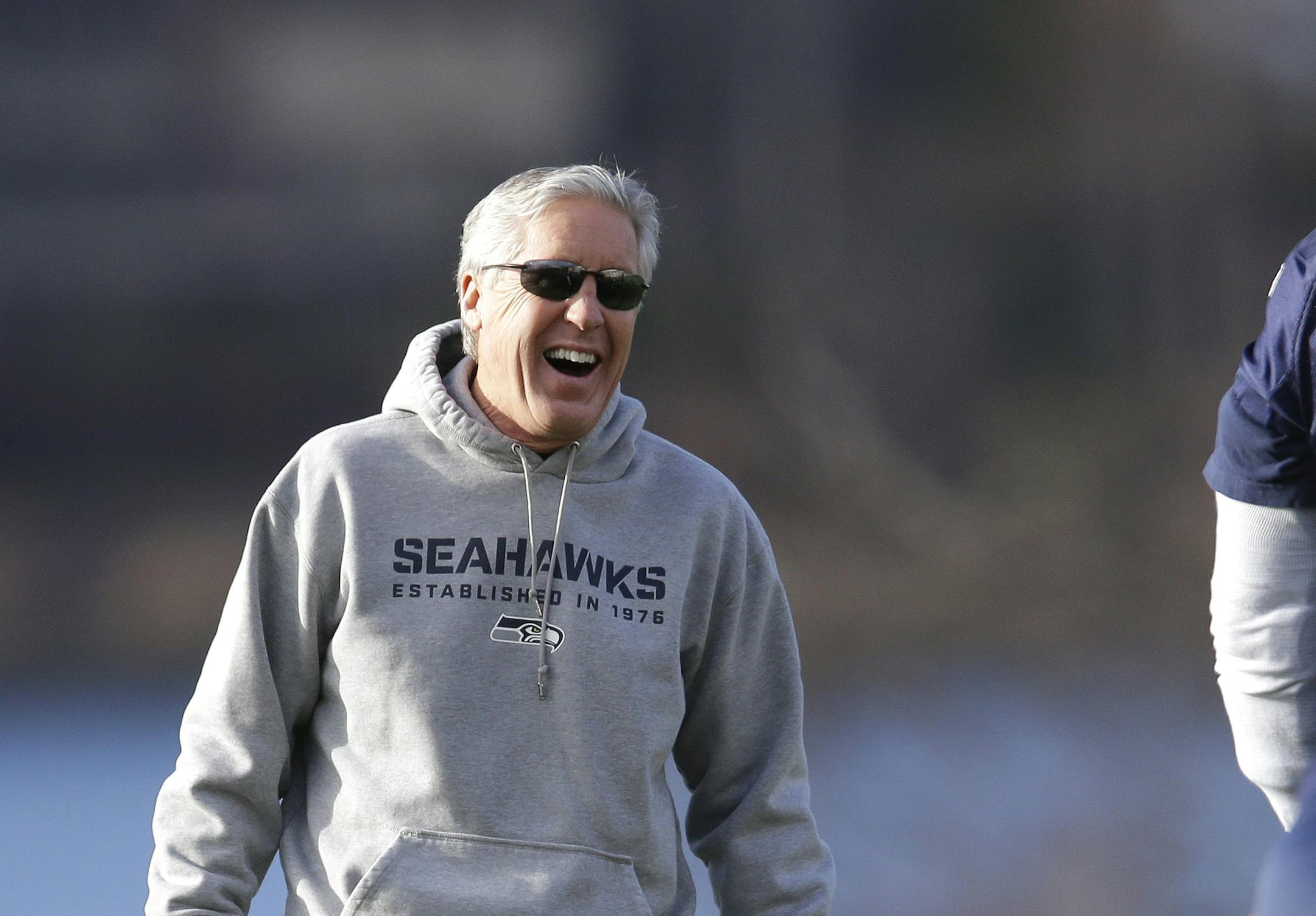 Seattle Seahawks coach Pete Carroll, left, laughs as he stands near tackle Paul McQuistan (67) during stretching drills before NFL football practice, Friday, Jan. 3, 2014, in Renton, Wash. Seattle plays at home in a playoff game on Jan. 11. (AP Photo/Ted S. Warren)